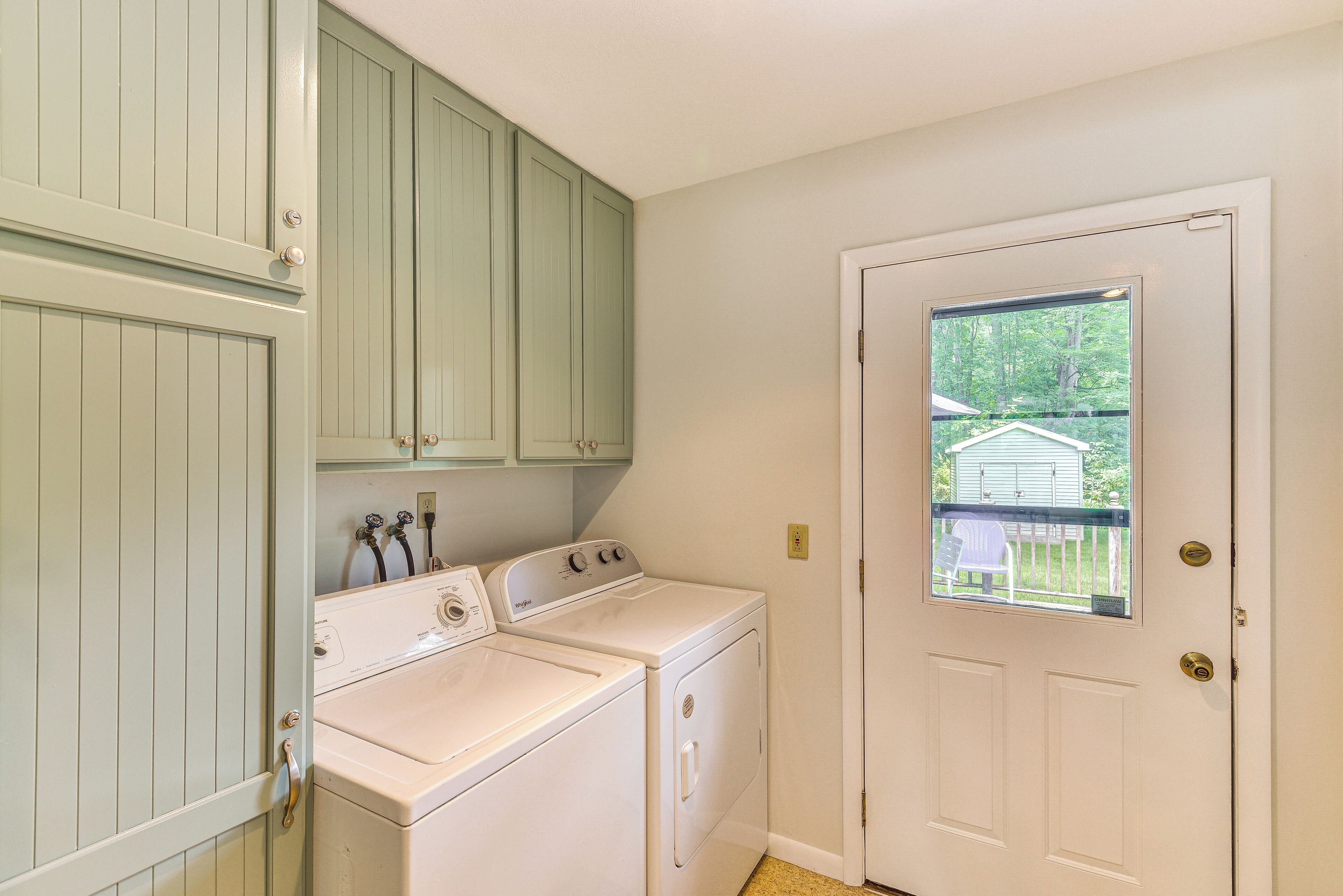 A laundry room with a washer and dryer, a door with a window, and green cabinets.