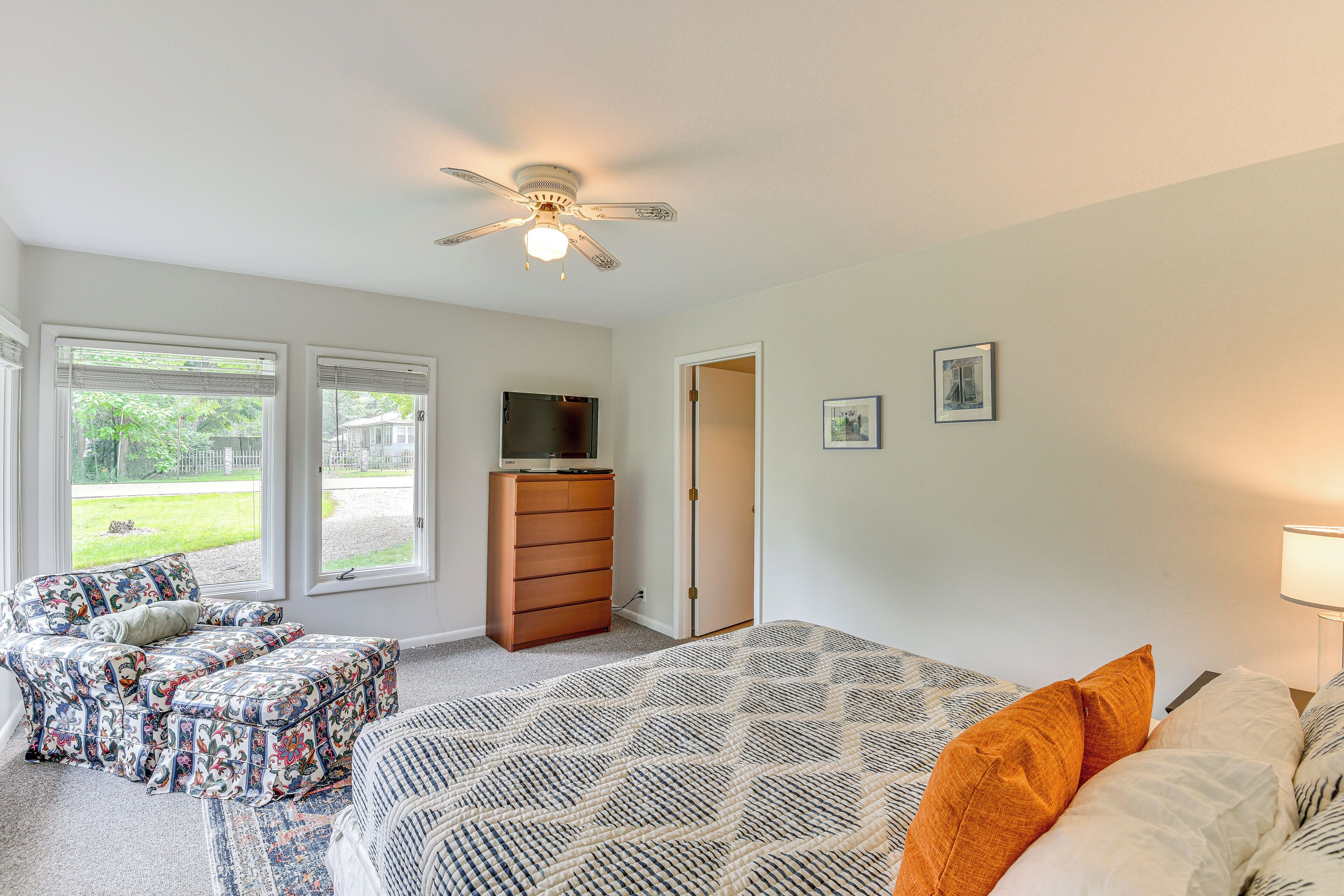 A bedroom with a bed, a dresser, a TV, and a chair.