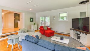 A modern living room with a sofa, red armchair, and a TV. - Charming Union Pier Home w/ Deck: Half-mi to Beach (Union Pier)