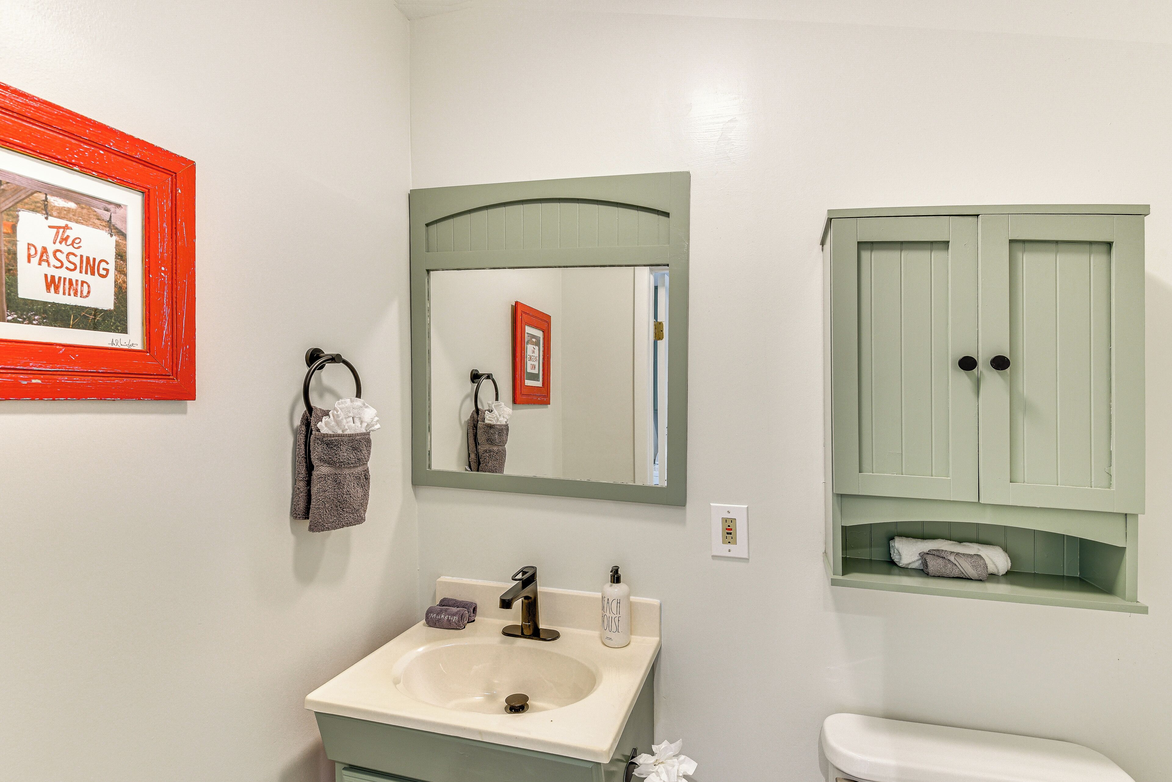 Une salle de bain équipée d’un lavabo, d’un miroir, d’un porte-serviettes et d’un meuble de rangement.