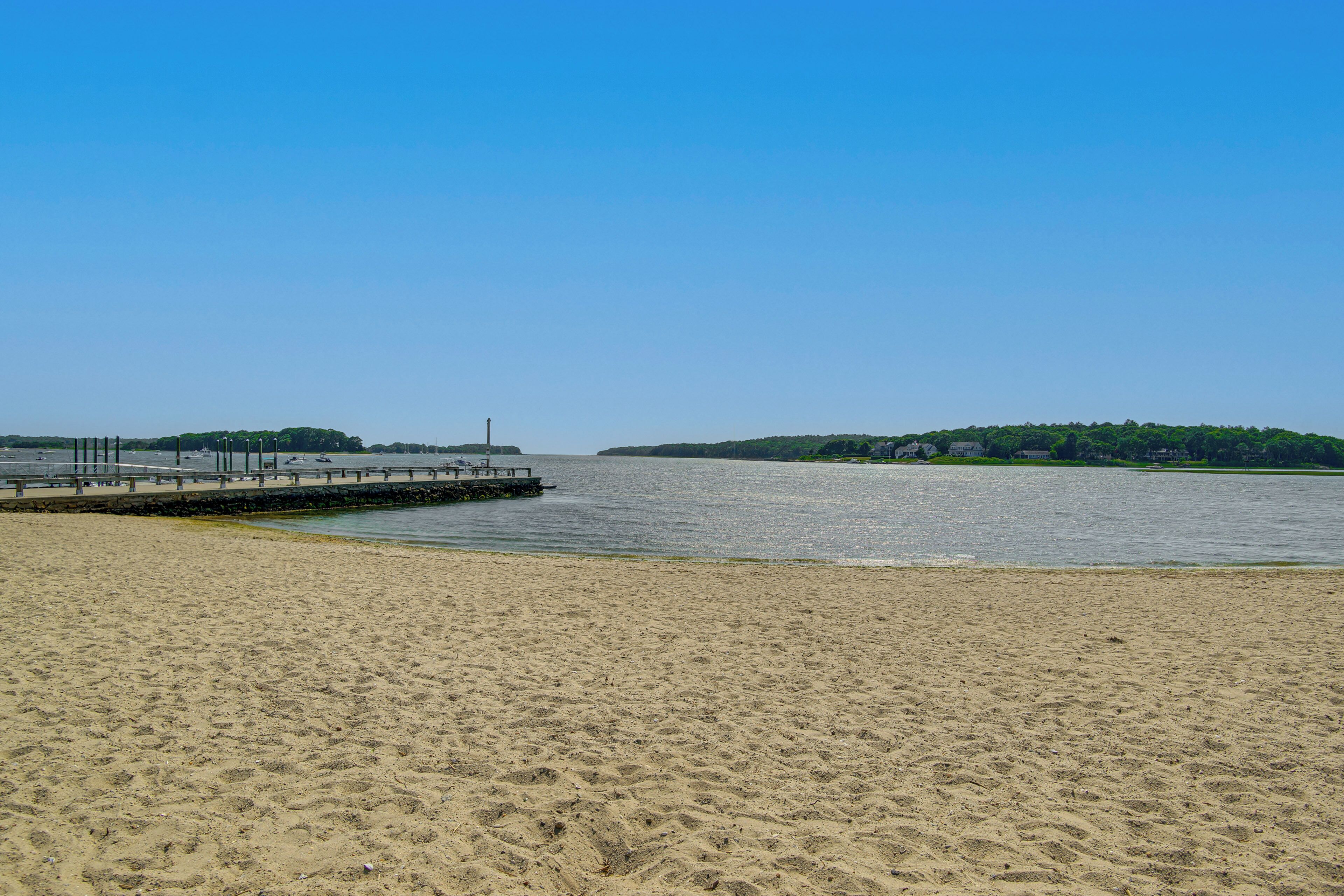 A sandy beach with a pier extending into calm water.