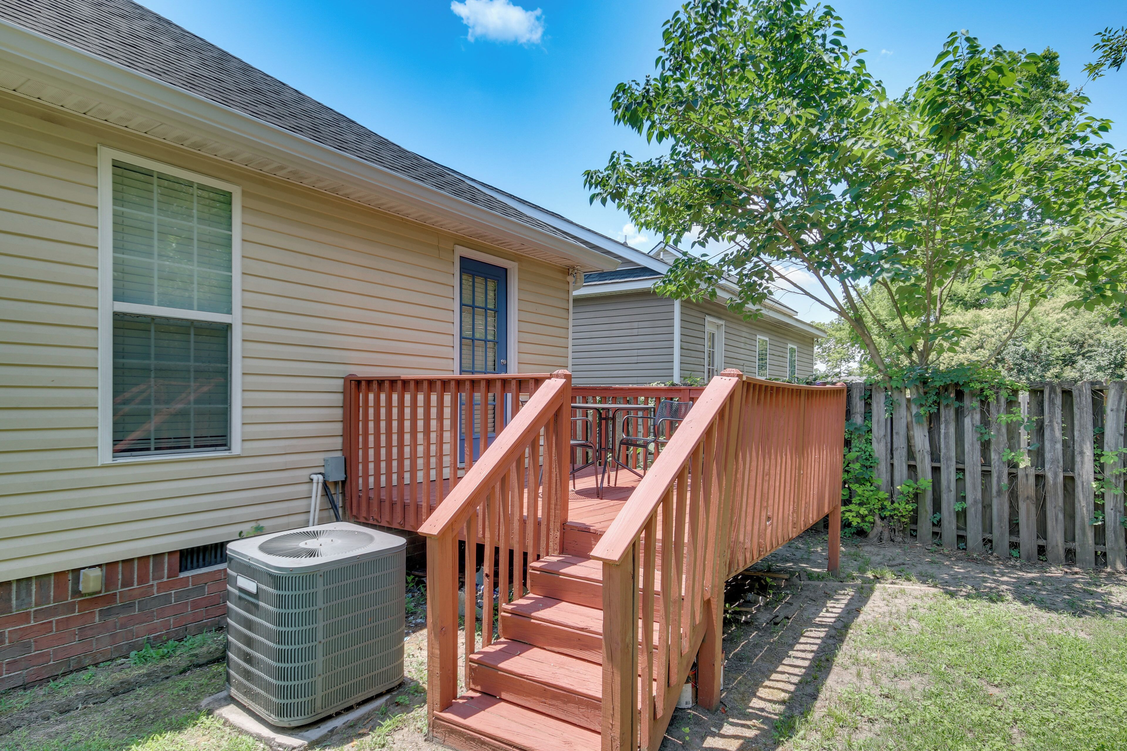 A residential house with a wooden deck, a brick foundation, and a large air conditioning unit.