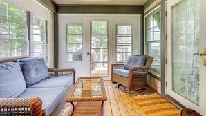 A covered porch with wicker furniture, a glass table, and large windows. - Lakefront New London Retreat w/ Dock & Hot Tub! (New London)