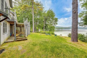 A house with a deck, a grassy yard, and a view of a lake.