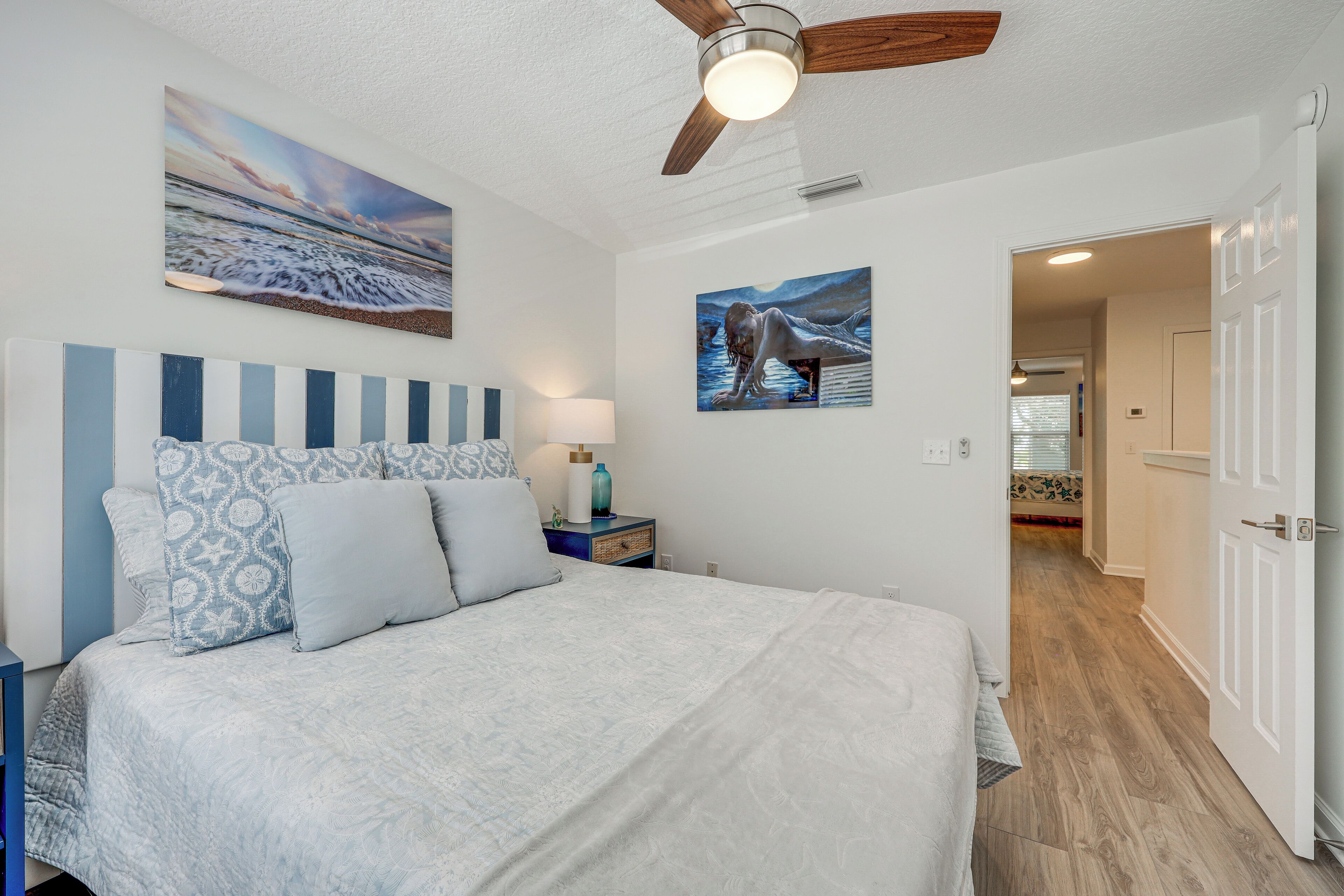 A bedroom with a bed, a nightstand, a lamp, and a ceiling fan.