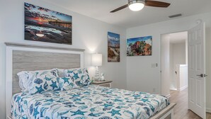 Un dormitorio con una cama, una mesita de noche, una lámpara de pared y un ventilador de techo.