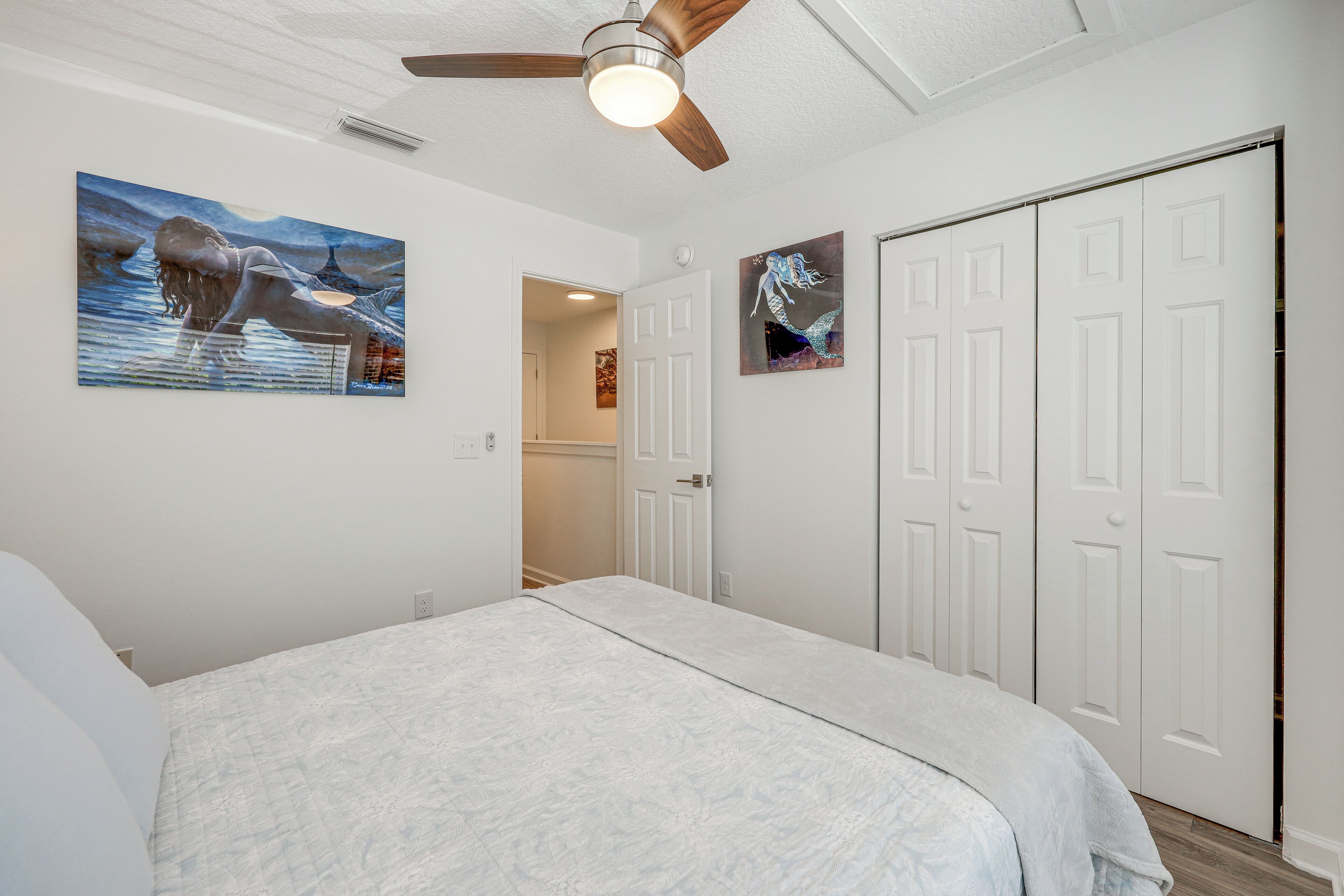 A bedroom with a bed, a ceiling fan, and two doors.