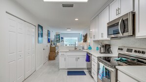 Una cocina moderna con armarios blancos, electrodomésticos de acero inoxidable y una isla central.