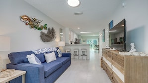 Una sala de estar moderna con un sofá azul, un mueble de madera y un televisor de pantalla plana.