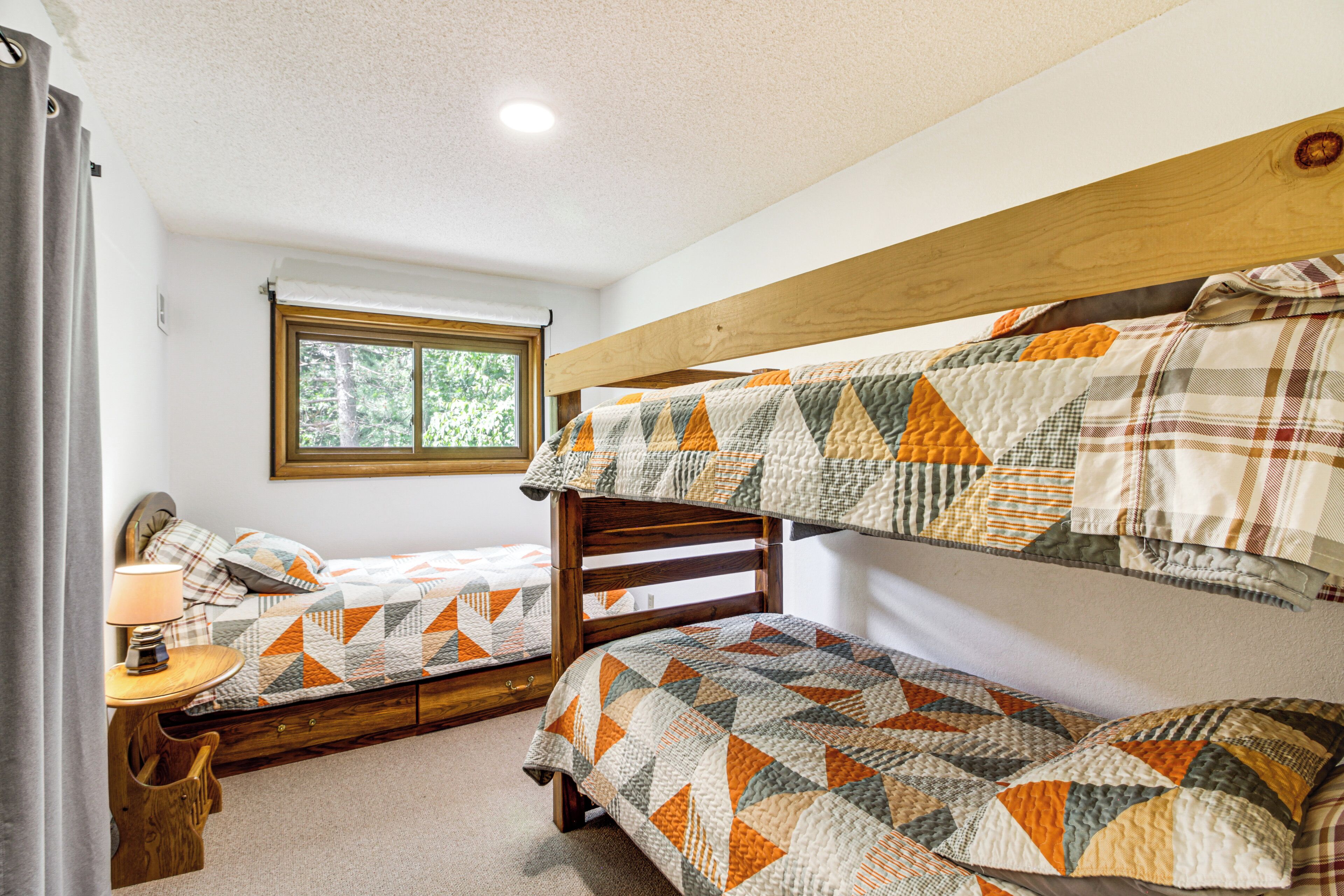 A room with bunk beds, a window, a lamp, and a wooden headboard.