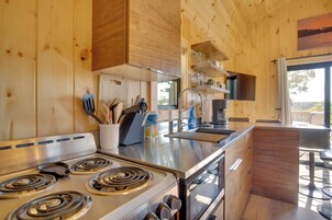Una cocina moderna con paredes de madera, electrodomésticos de acero inoxidable y vistas al exterior.