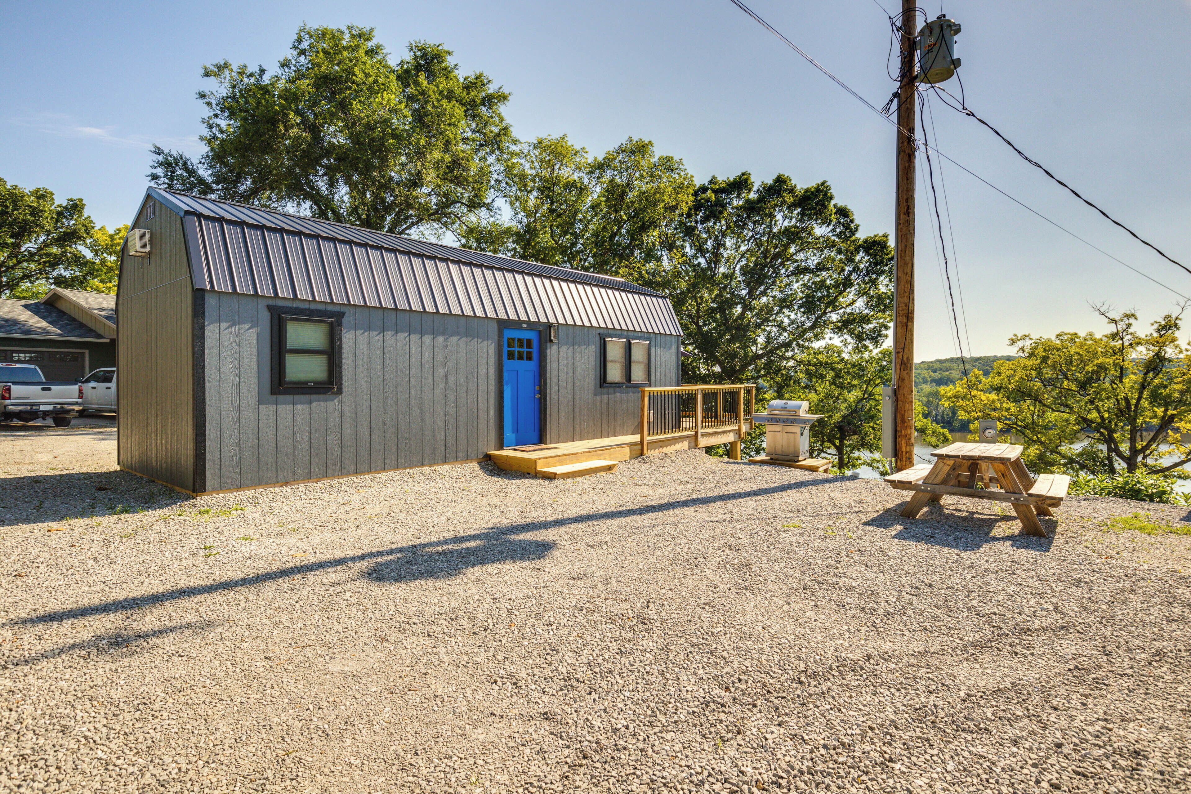 A small, single-story building with a blue door and a wooden deck.