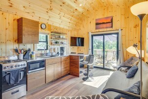 A modern kitchen with wooden cabinets, a stove, microwave, and a dining area with a sofa and chairs.