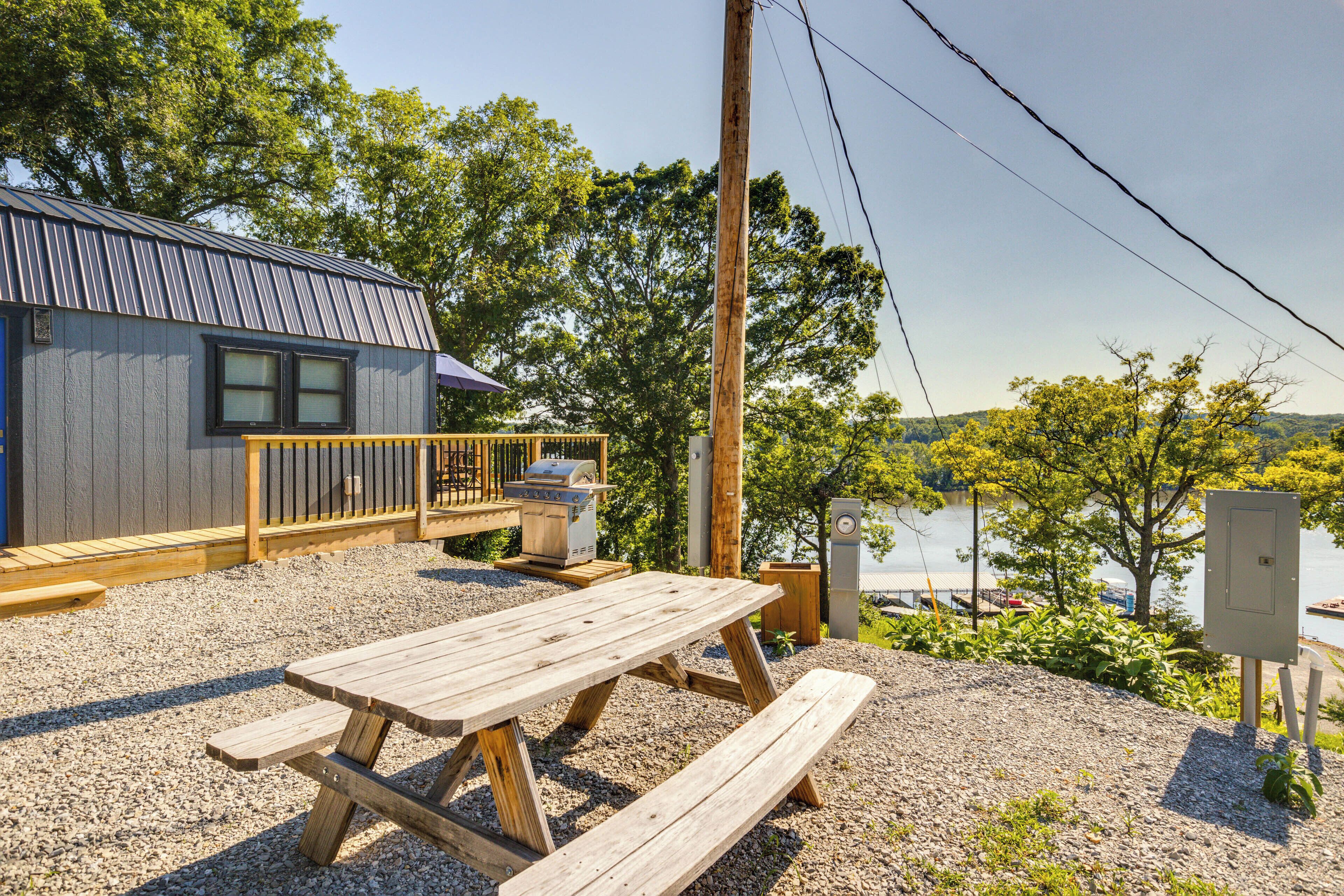 A wooden deck with a picnic table, a barbecue grill, and a view of a lake.