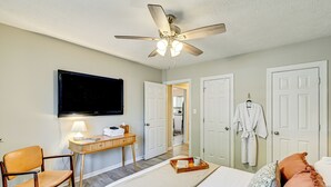 Une chambre d’hôtel équipée d’un lit, d’un bureau avec une lampe, d’une télévision et d’un ventilateur de plafond.