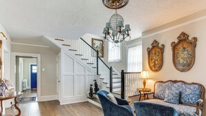 Ein geräumiges Wohnzimmer mit Holzdielen, einer imposanten Treppe und einem Chandelier.