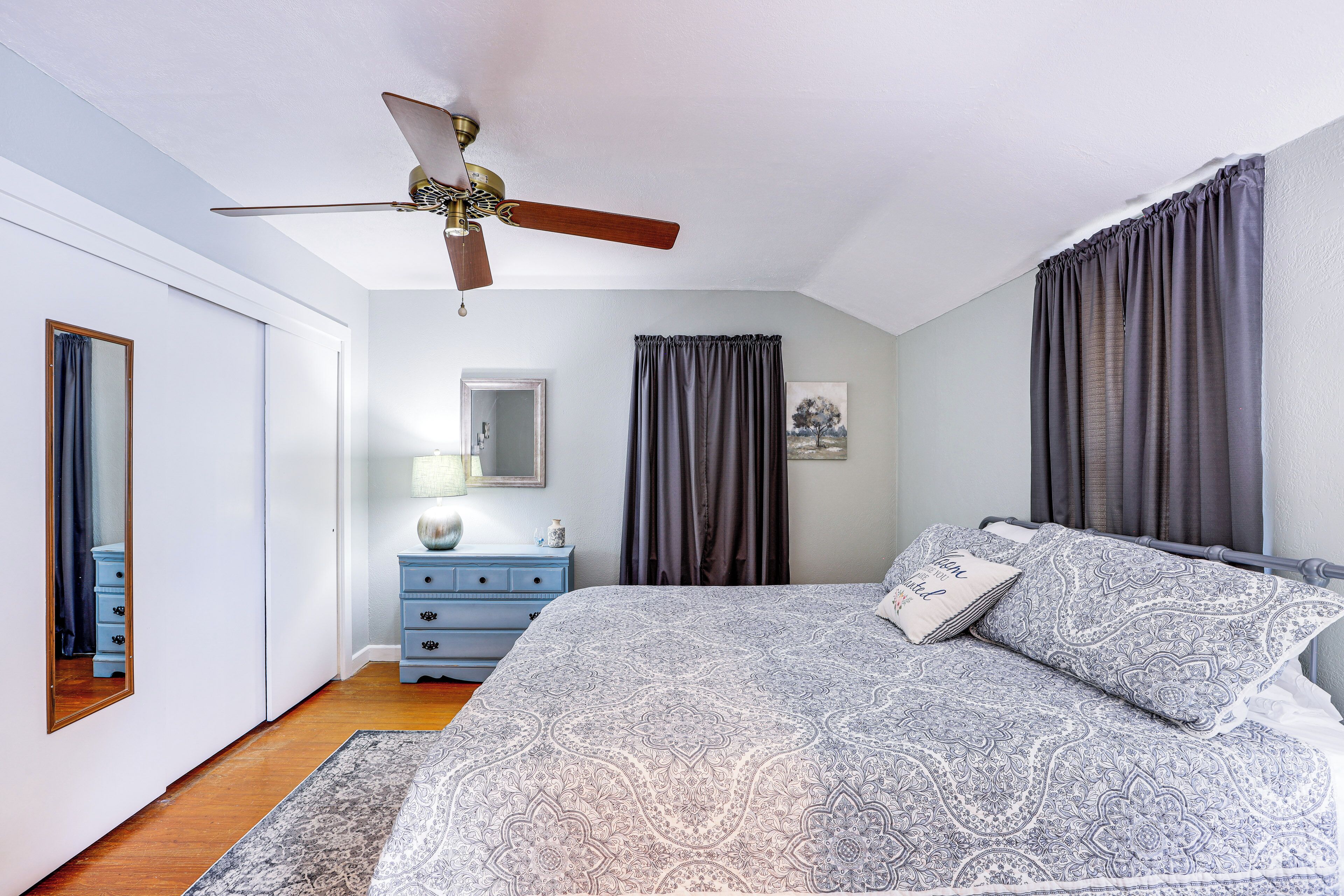 Une chambre à coucher avec un lit, un ventilateur de plafond, une commode et un miroir.