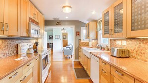 A kitchen with wooden cabinets, a stainless steel oven, a toaster, and a tiled backsplash. - Boathouse & Dock: Riverfront Dunnellon Getaway! (Dunnellon)