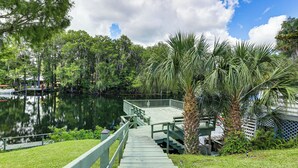 A wooden dock extending into a calm lake surrounded by lush greenery and trees. - Boathouse & Dock: Riverfront Dunnellon Getaway! (Dunnellon)