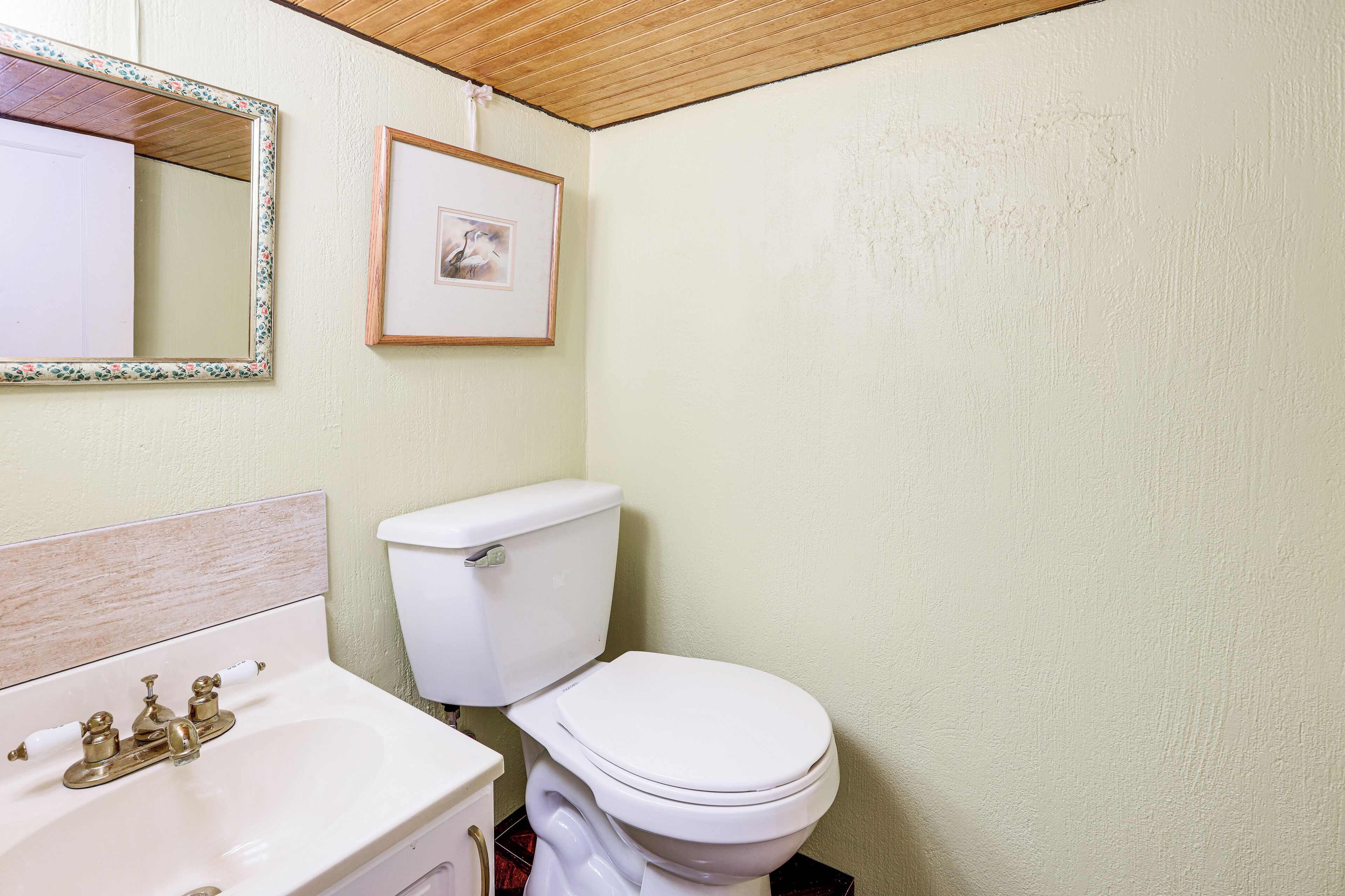 A bathroom with a white sink, a toilet, and a framed picture on the wall.