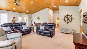 A spacious living room with leather sofas, a wooden ceiling, and a sail wheel decoration. - Boathouse & Dock: Riverfront Dunnellon Getaway! (Dunnellon)