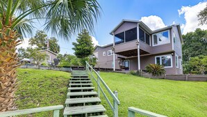 A two-story house with a wooden staircase leading to a deck. - Boathouse & Dock: Riverfront Dunnellon Getaway! (Dunnellon)
