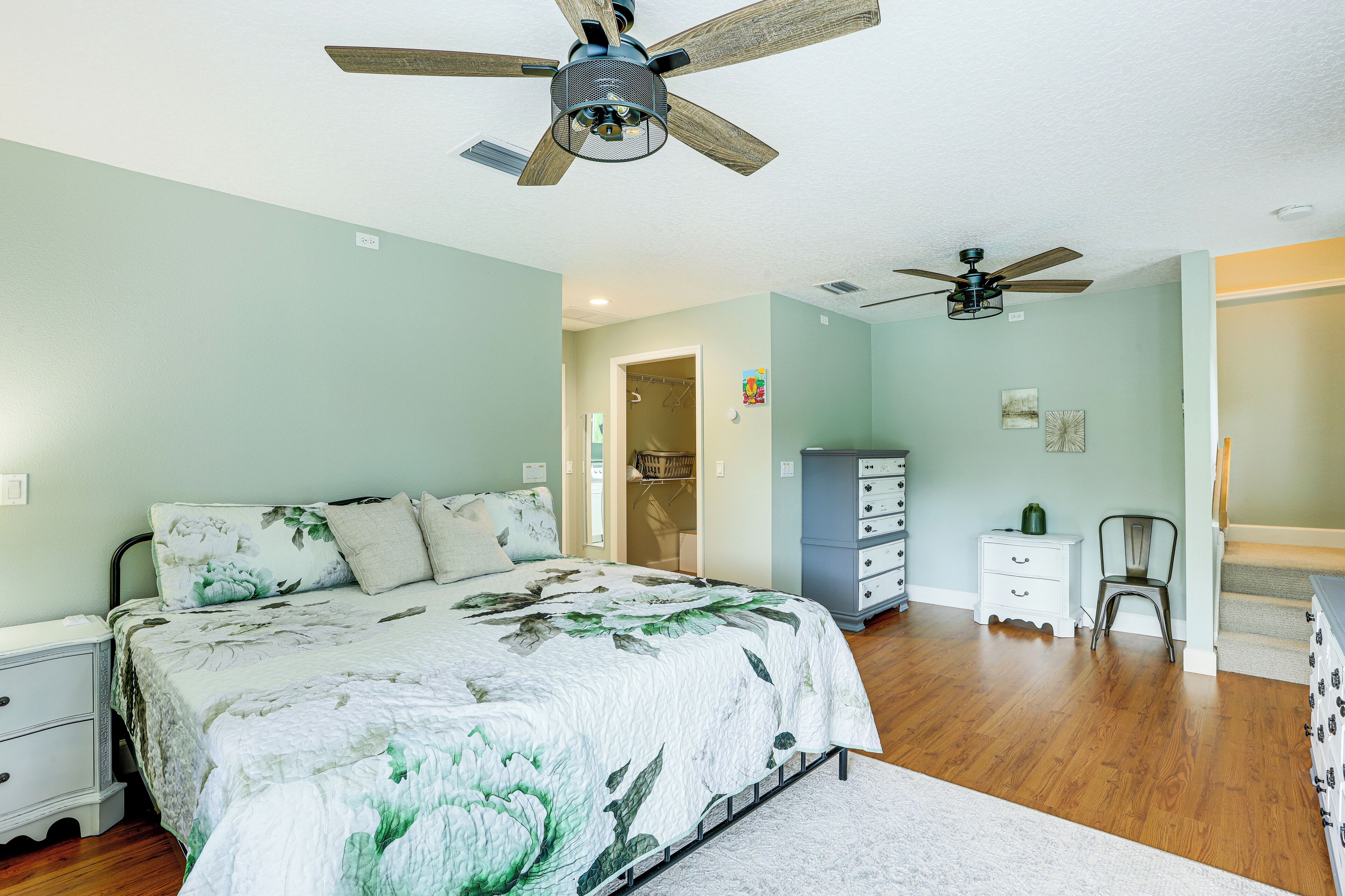 Un dormitorio con una cama, ventilador de techo, cómoda y una silla.