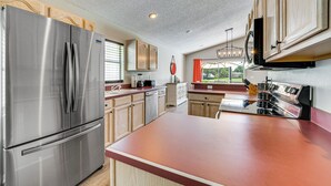 A modern kitchen with stainless steel appliances, wooden cabinets, and a large island.