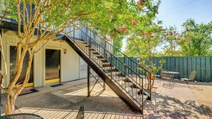 A building with a staircase leading to an upper level, a patio area with a table and chairs, and a tree with pink flowers. - Dallas Condo in Walkable Knox Street District! (Dallas)