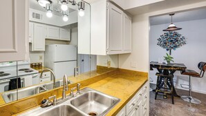 A modern kitchen with a stainless steel sink, white cabinets, and a yellow marble countertop. - Dallas Condo in Walkable Knox Street District! (Dallas)