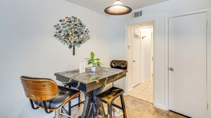 A dining area with a wooden table, two chairs, a pendant light, and a decorative wall piece. - Dallas Condo in Walkable Knox Street District! (Dallas)