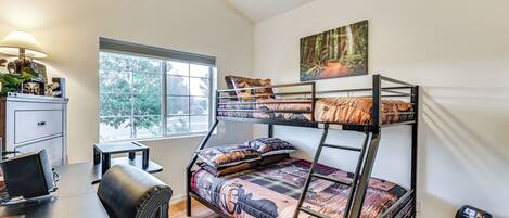 A bunk bed room with a desk, chair, and a fan.