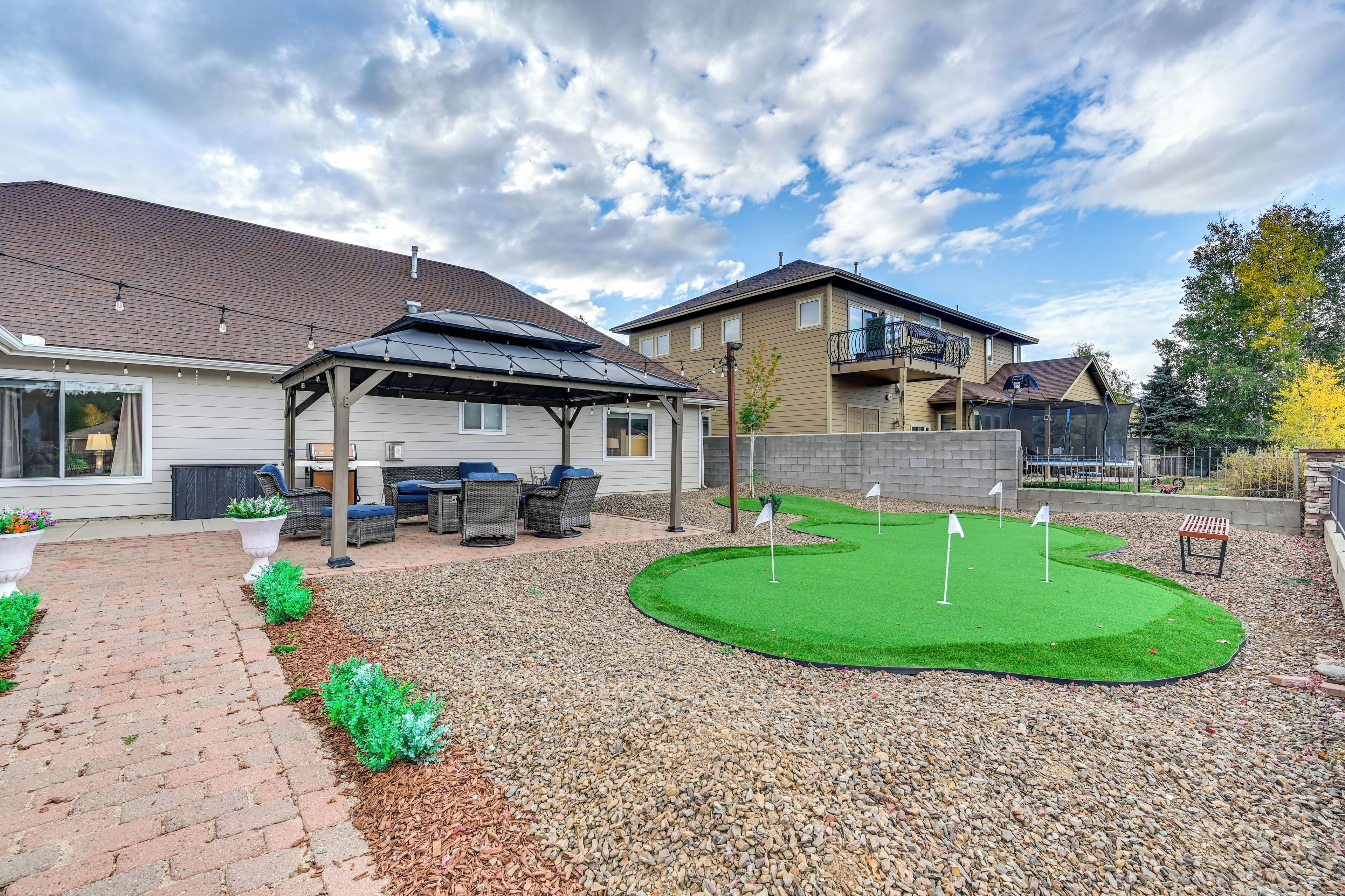 Un quartier résidentiel doté d’un patio, d’un espace extérieur aménagé pour s’asseoir, d’un petit terrain d’entraînement au golf et d’une structure couverte.