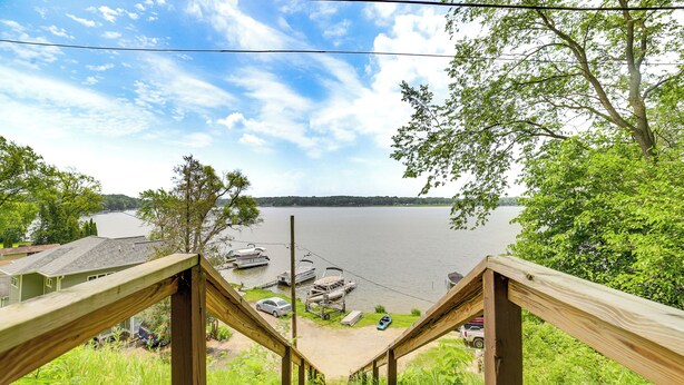 A wooden staircase leading to a dock area with boats, surrounded by greenery and a lake view. - Group Retreat on Wolf Lake! Paddle, Fish & BBQ (Jackson)