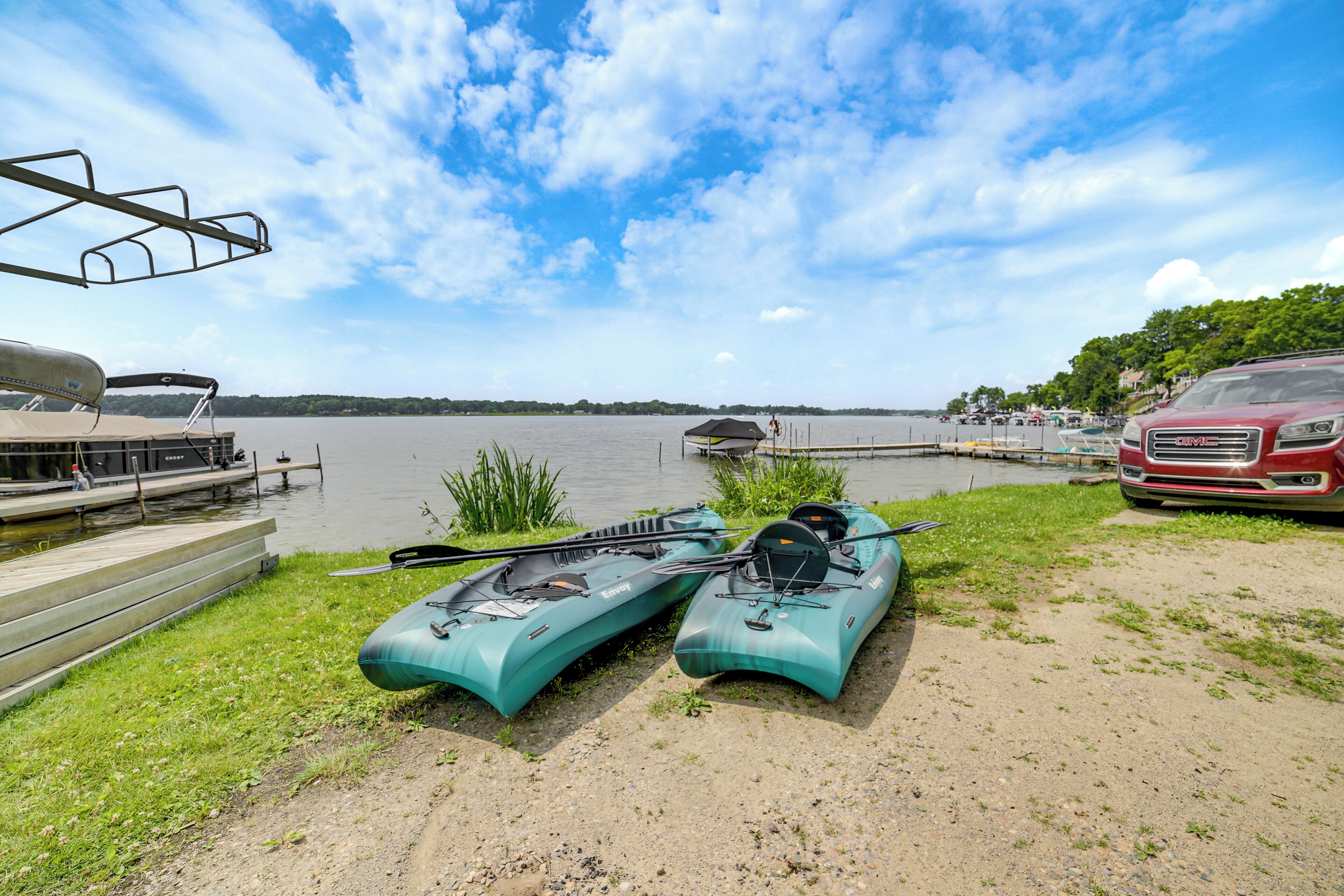 A lakeside setting with kayaks and a red vehicle parked near the water.
