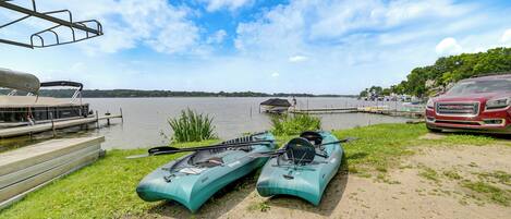 A lakeside setting with kayaks and a red vehicle parked near the water.