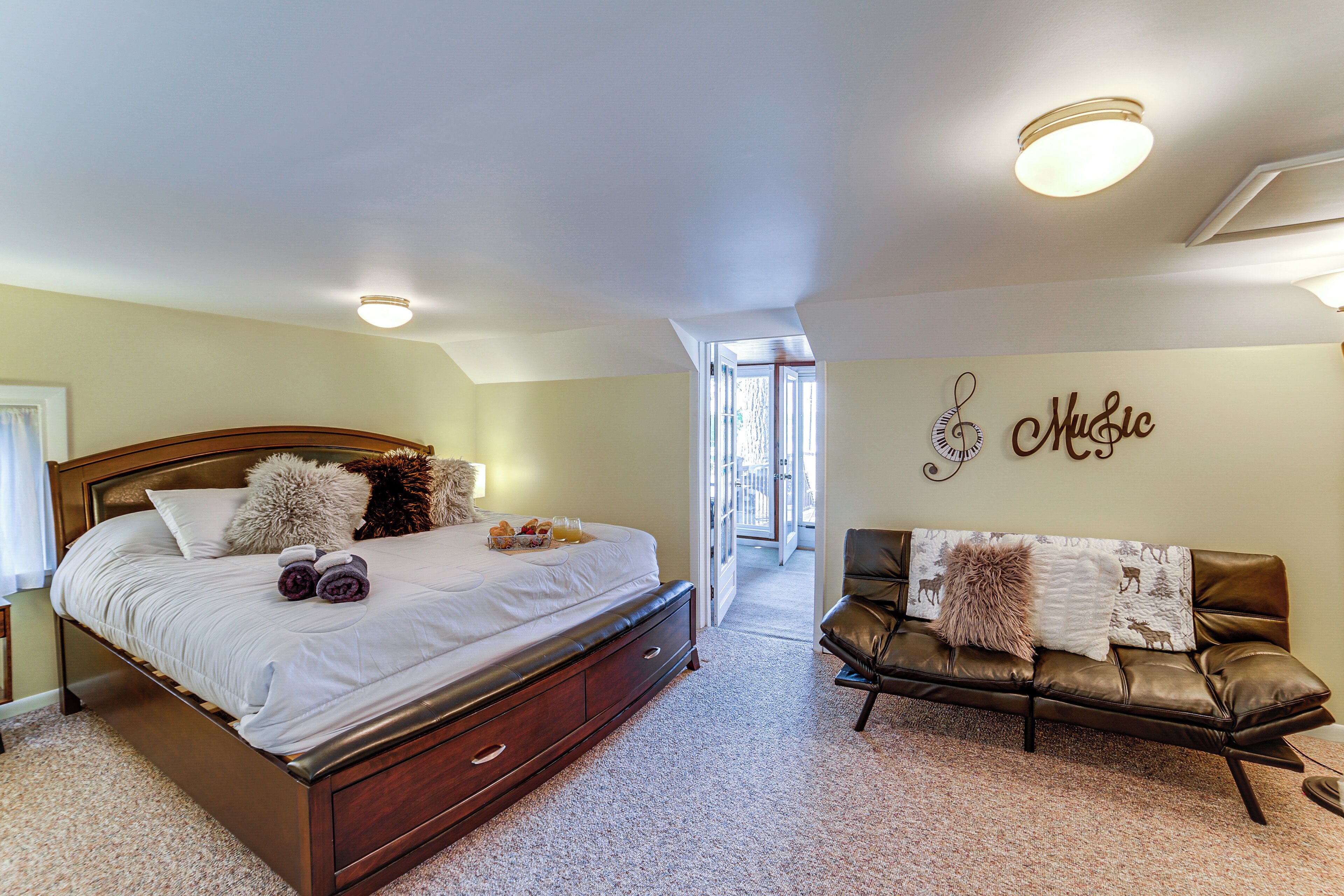 A bedroom with a large bed, a leather sofa, and a wall with a 'Music' sign.