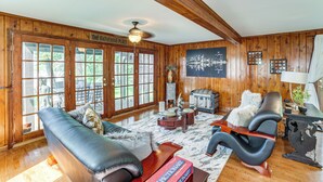 A spacious living room with a fireplace, leather sofas, and a large window with a view of trees. - Group Retreat on Wolf Lake! Paddle, Fish & BBQ (Jackson)