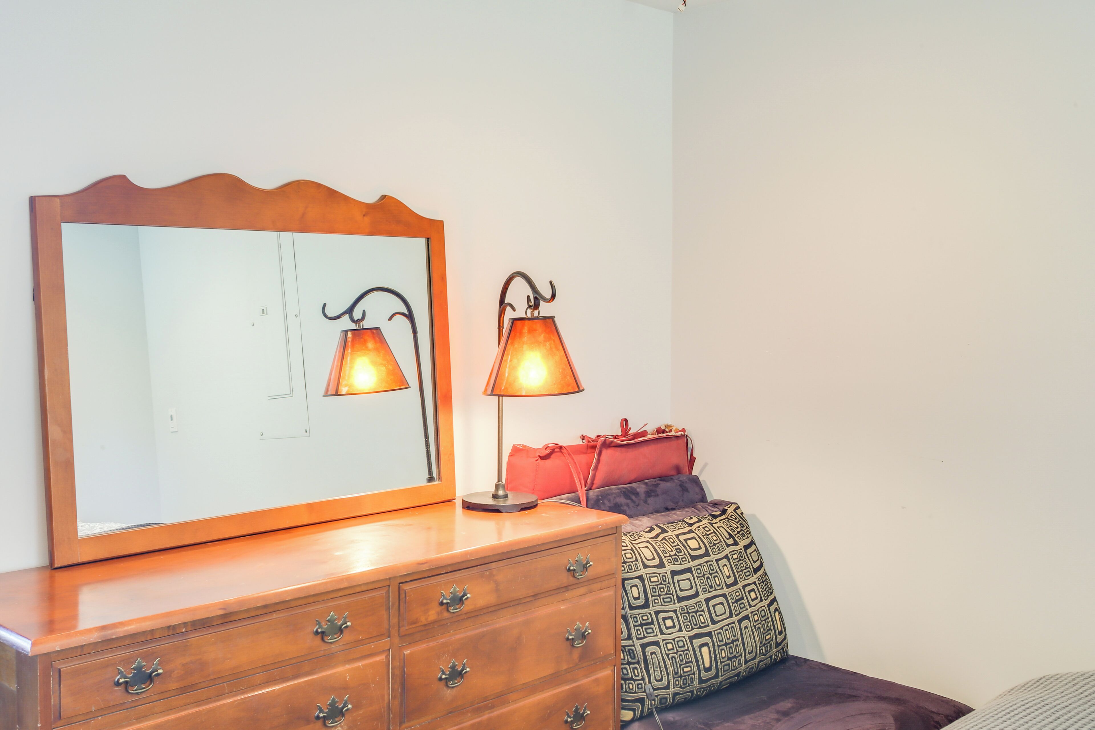 A wooden dresser with a mirror and two table lamps.