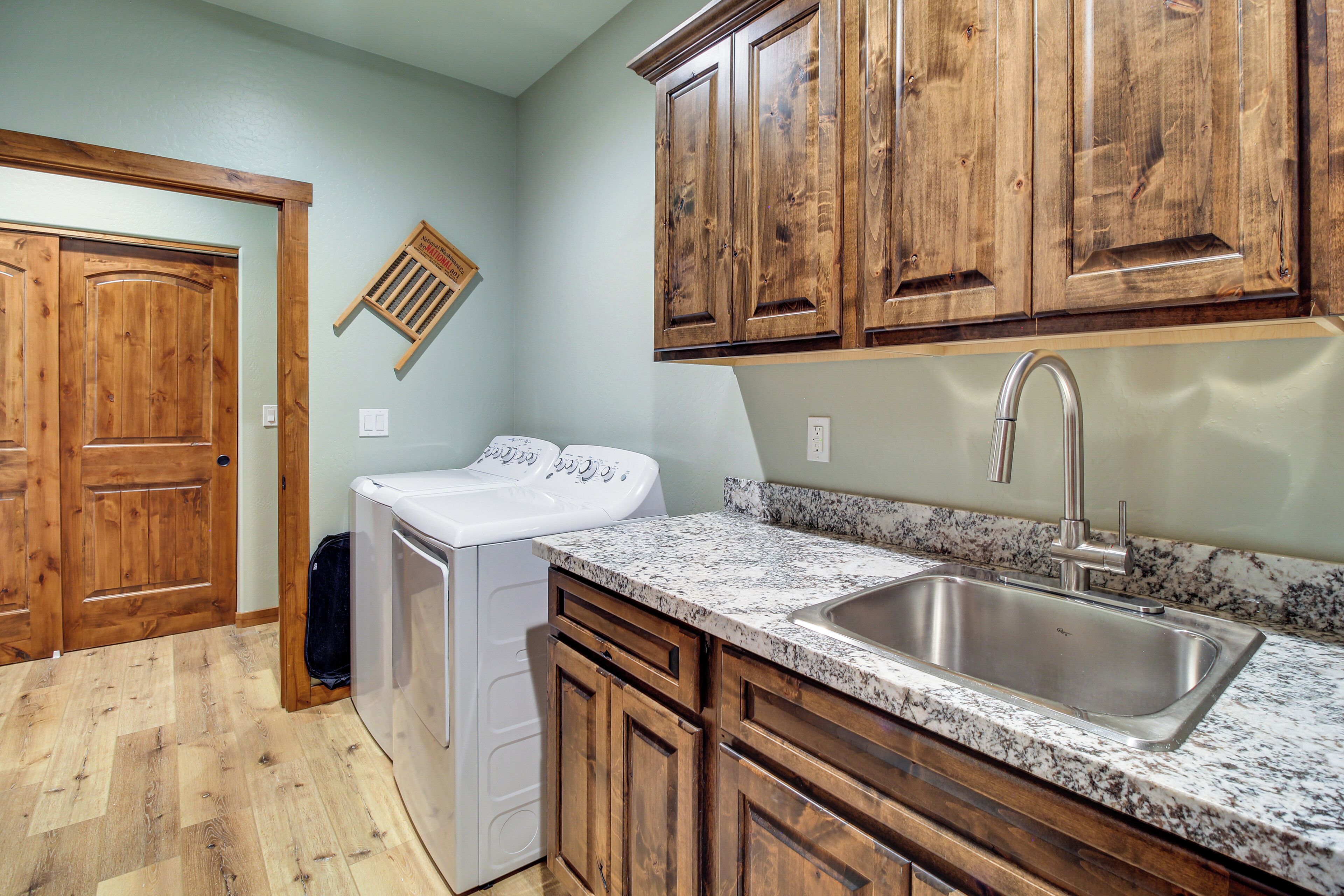 A kitchen with wooden cabinets, a stainless steel sink, and a washing machine.