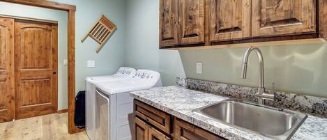 A kitchen with wooden cabinets, a stainless steel sink, and a washing machine.