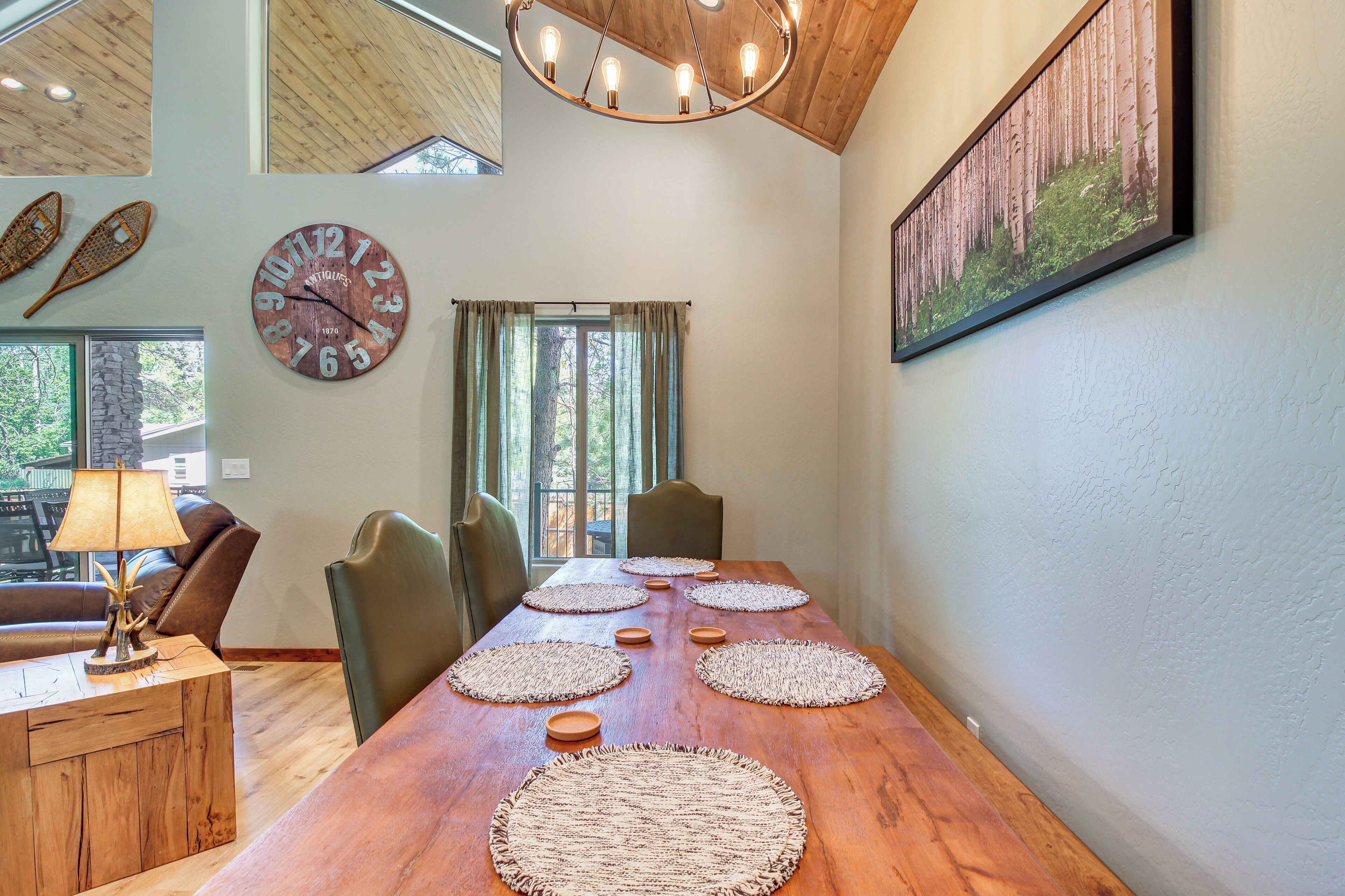 A dining area with a wooden table, woven placemats, and a large wall clock.