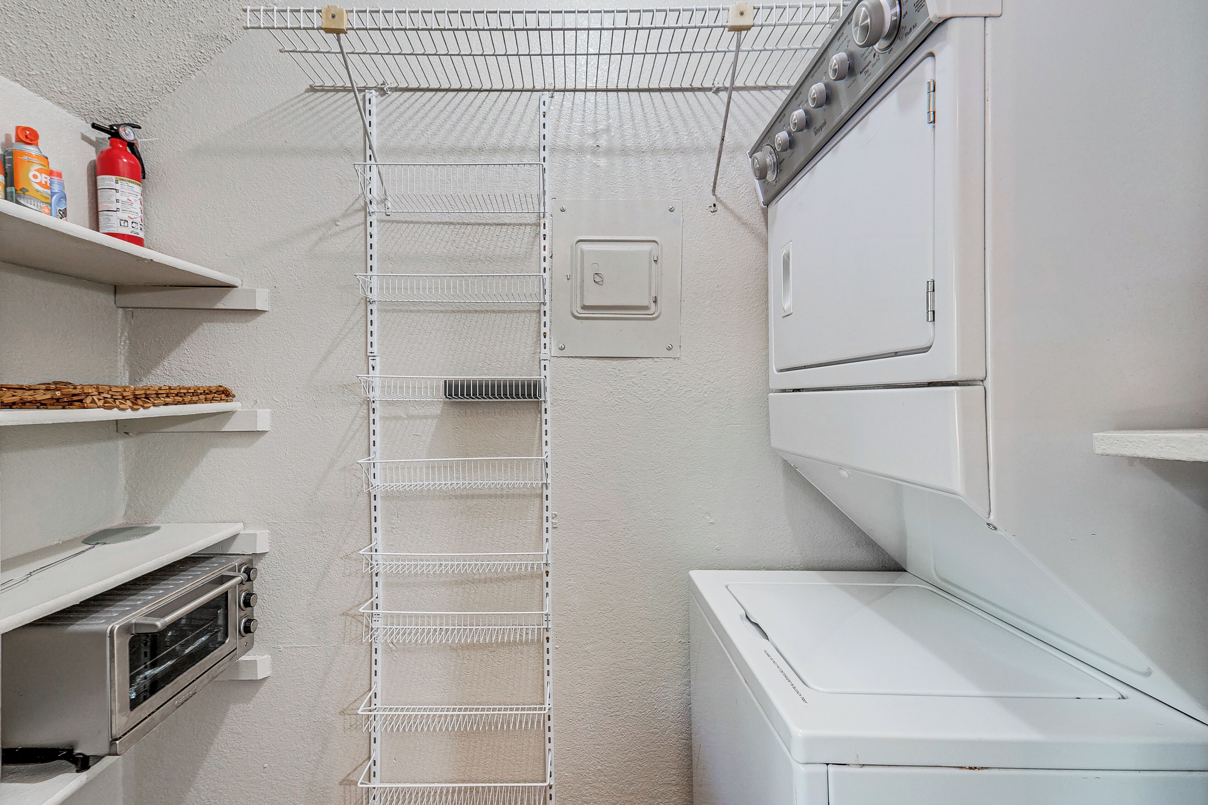 A laundry room with a white washing machine, a dryer, and a shelf with cleaning supplies.