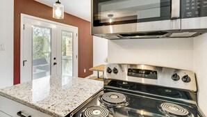 Une cuisine équipée d’une cuisinière en acier inoxydable, d’un four à micro-ondes et d’un luminaire suspendu.