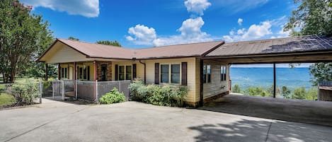 A two-story house with a covered porch and a view of the ocean.