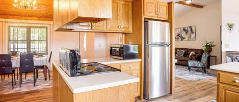 A kitchen with wooden cabinets, a stainless steel refrigerator, and a dining area with a table and chairs.