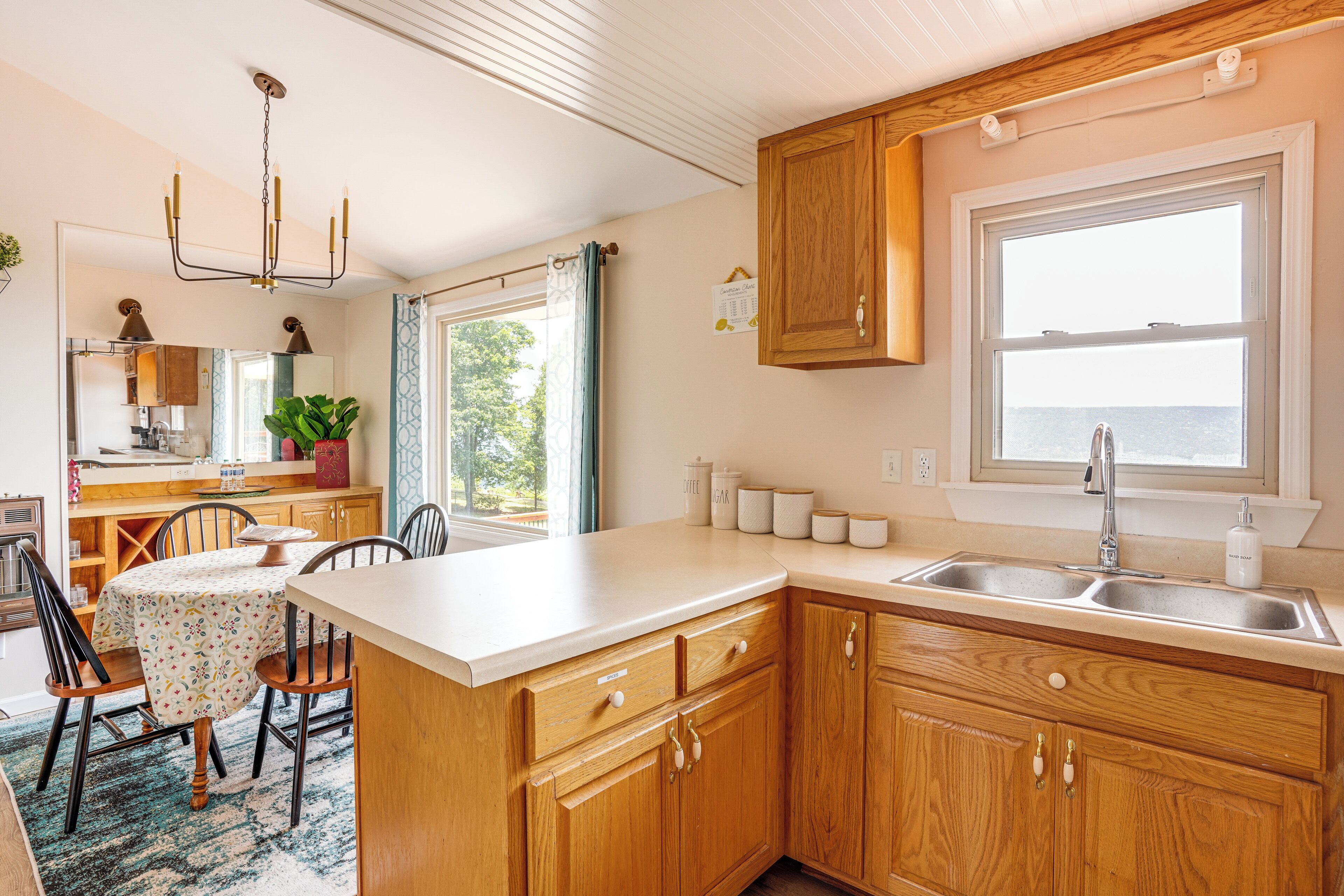 A kitchen with wooden cabinets, a white countertop, a sink, and a window with a view of the sea.