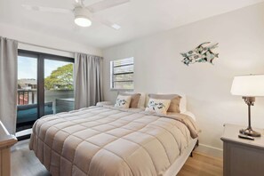 A bedroom with a large bed, a ceiling fan, a window with blinds, and a wall-mounted lamp. - E-234 -Deluxe Updated Condo With Beautiful Views! (Naples)