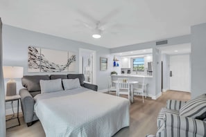 A modern bedroom with a large bed, a desk, and a chair, a grey sofa, and a striped armchair. - F-237 - Deluxe Condo - Amazing Views and Sleeps 6 (Naples)