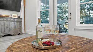 A round wooden table with a bottle of Cooper wine, two glasses of wine, and a wooden board with berries. - Beach Across St | Pool + Hot Tub | Sleeps 12 (Gulf Shores)